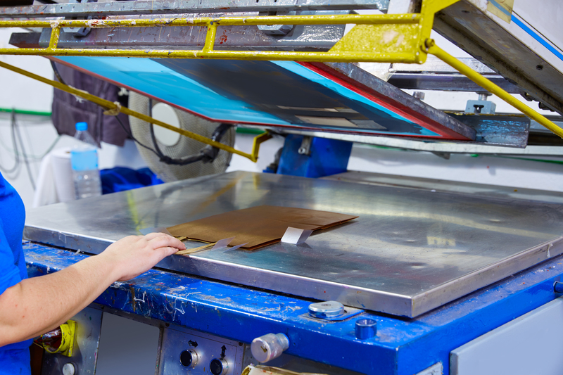 Serigraphy print bags machine in printing factory with operator female hand